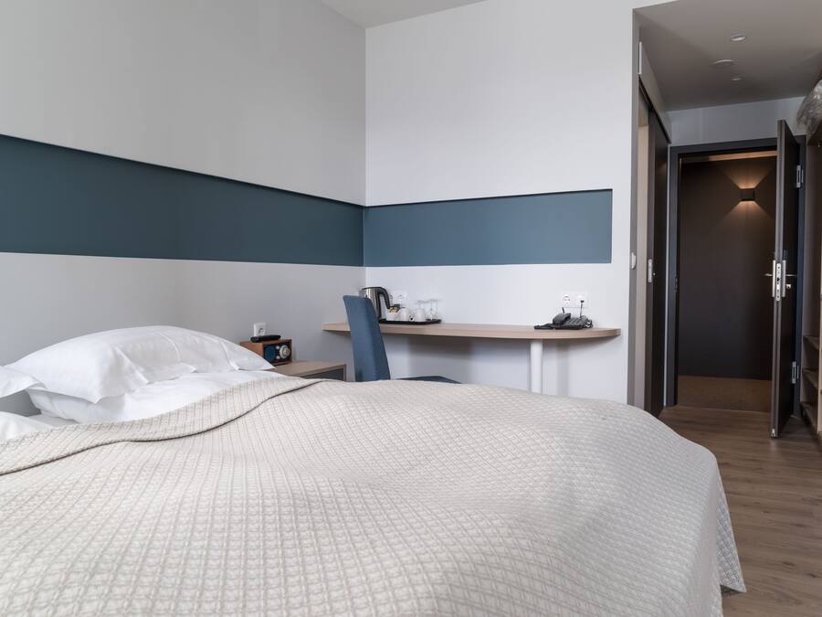 A modern hotel room with a large bed, a desk, and a chair.