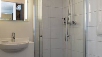 A modern bathroom with a glass-enclosed shower, a sink, and a toilet.