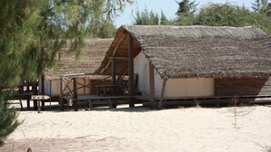 Un bâtiment rustique à toit de chaume, doté d’une terrasse en bois et d’une enseigne indiquant le numéro « 2 ».