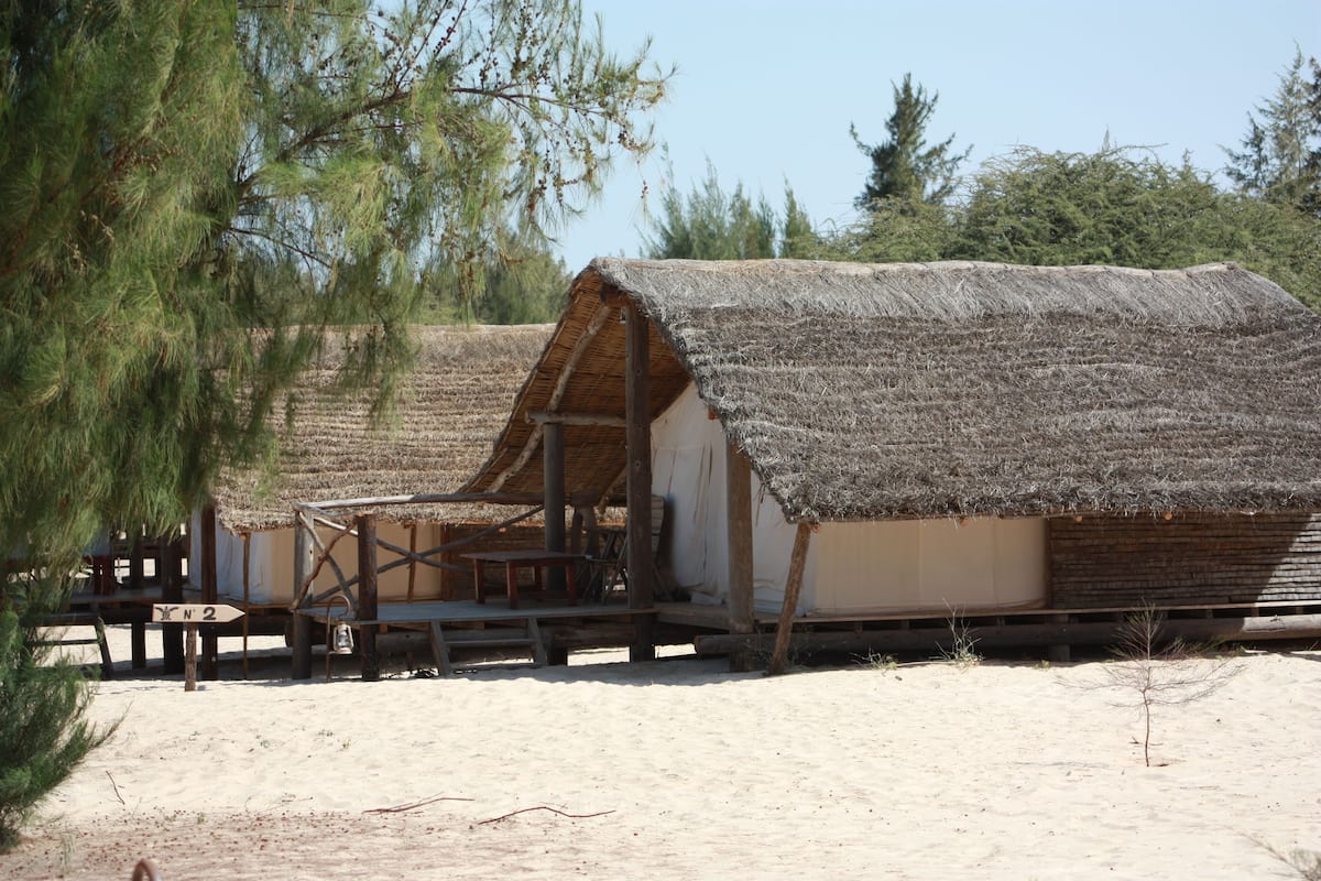 A rustic thatched-roof building with a wooden deck and a sign indicating 'No 2'.
