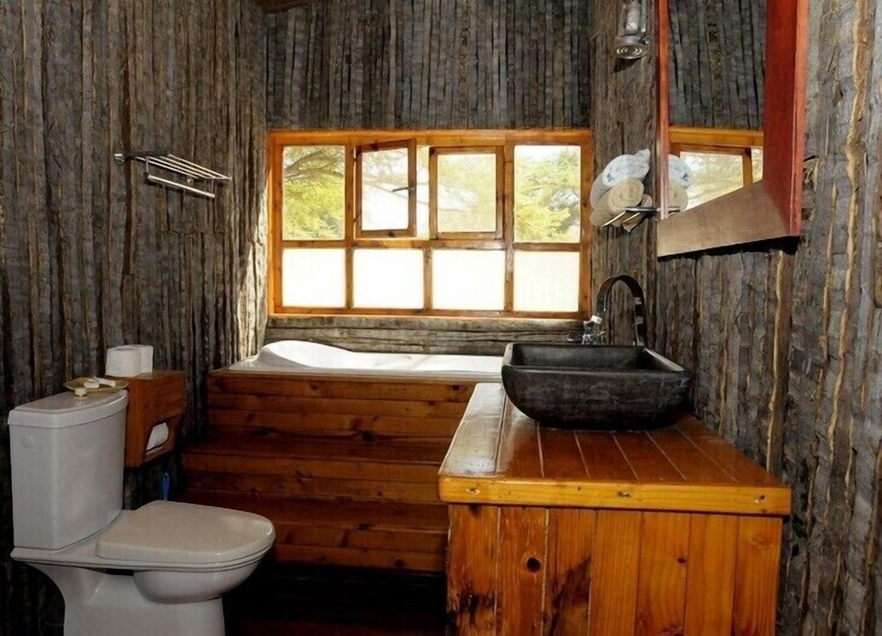 Un baño rústico con inodoro de madera, un lavabo y una bañera.
