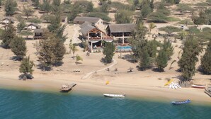Une propriété située sur la côte, comprenant plusieurs bâtiments, une piscine et des bateaux amarrés sur la plage.