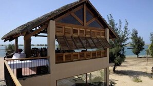 Une construction en bois dotée d’un toit de chaume, d’un balcon et offrant une vue sur la mer.