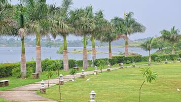 A pathway lined with palm trees and stone lanterns leading to a body of water.