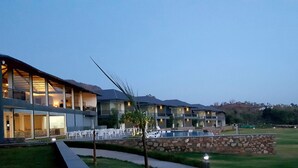 A resort with multiple buildings, outdoor seating, and a swimming pool.
