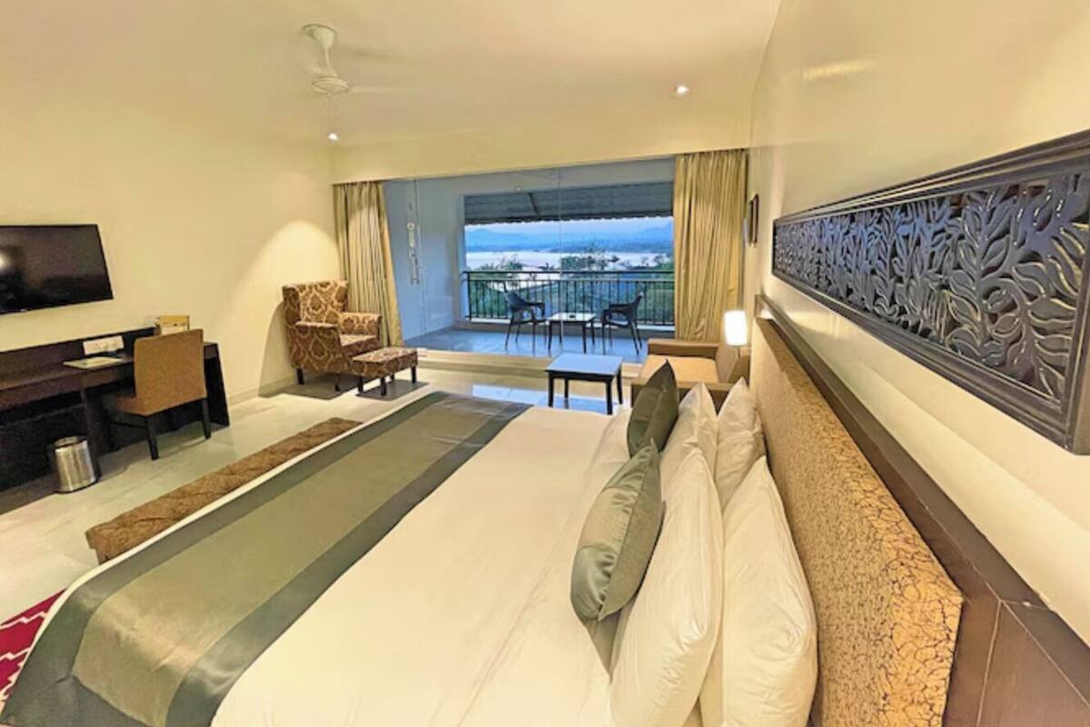 Une chambre d’hôtel dotée d’un grand lit, d’un bureau, d’une télévision, d’un balcon avec vue et d’un panneau décoratif mural.