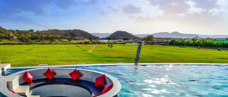 Una piscina al aire libre, sombrillas, sillones reclinables de piscina