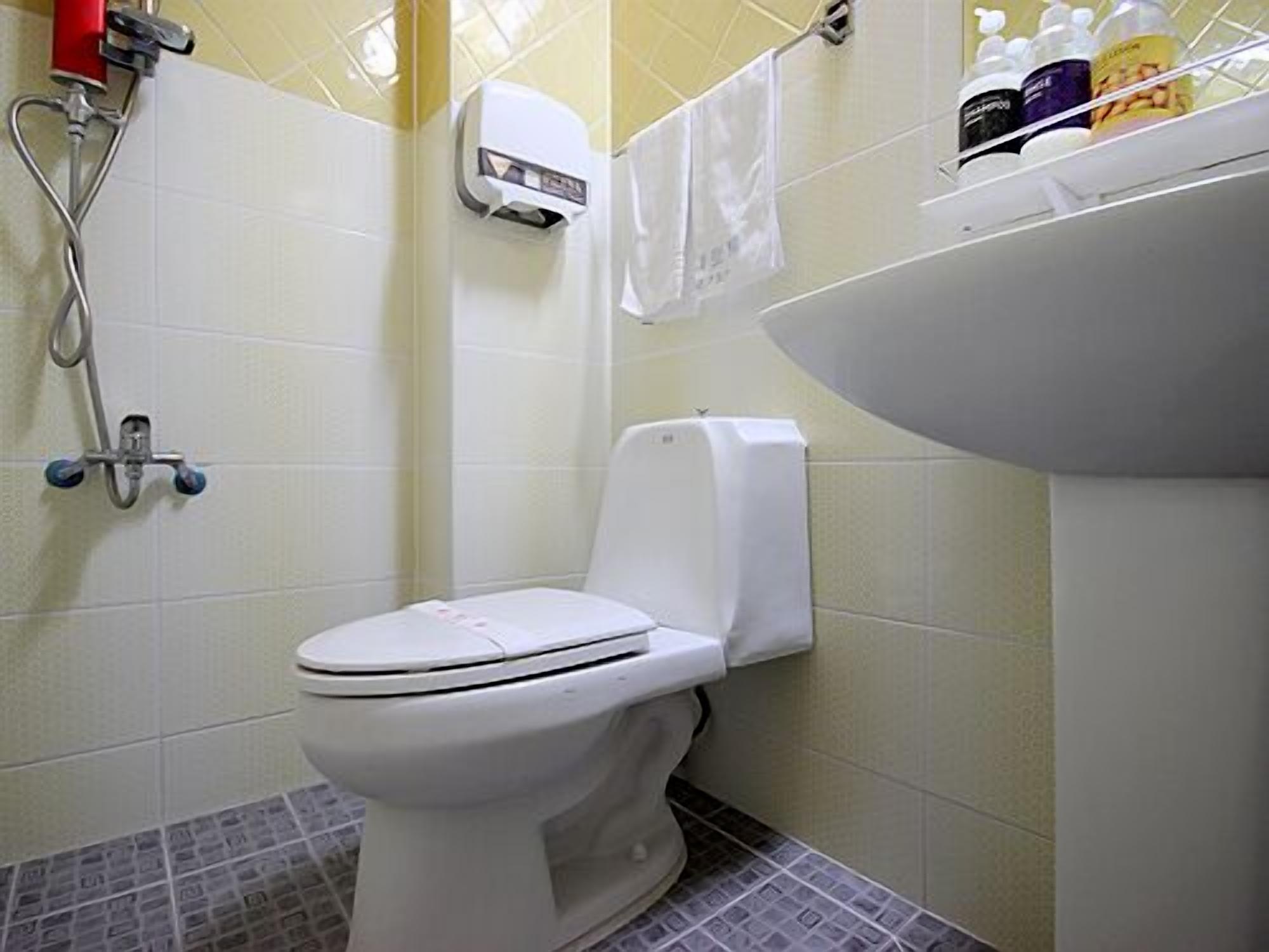 Un baño con inodoro, secamanos y lavamanos.