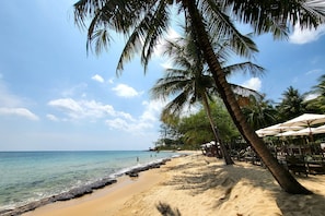 En privat strand, liggestole, parasoller, snorkling