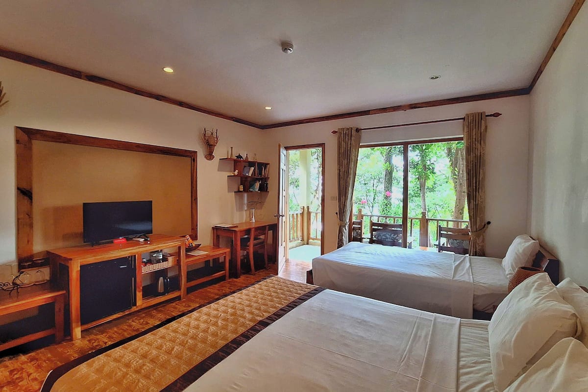 Habitación triple Deluxe, vista al jardín | Minibar, caja de seguridad en la habitación y escritorio