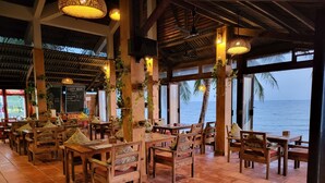 Un restaurante con mobiliario de madera y vista al mar.