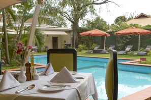 Una piscina al aire libre, sombrillas, sillones reclinables de piscina