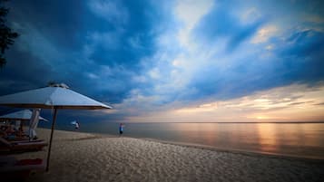 On the beach, white sand, sun loungers, beach umbrellas