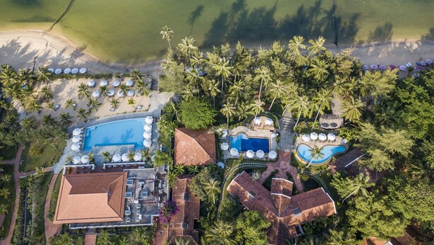 An aerial view of a resort with multiple swimming pools, a beach area, and lush greenery. - Cassia Cottage Resort and Spa (Phu Quoc)