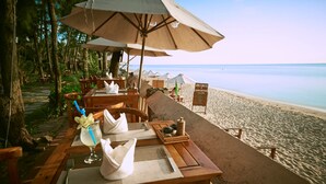 A beachside restaurant with wooden tables and chairs, umbrellas, and a sign reading "Spice Horse". - Cassia Cottage Resort and Spa (Phu Quoc)