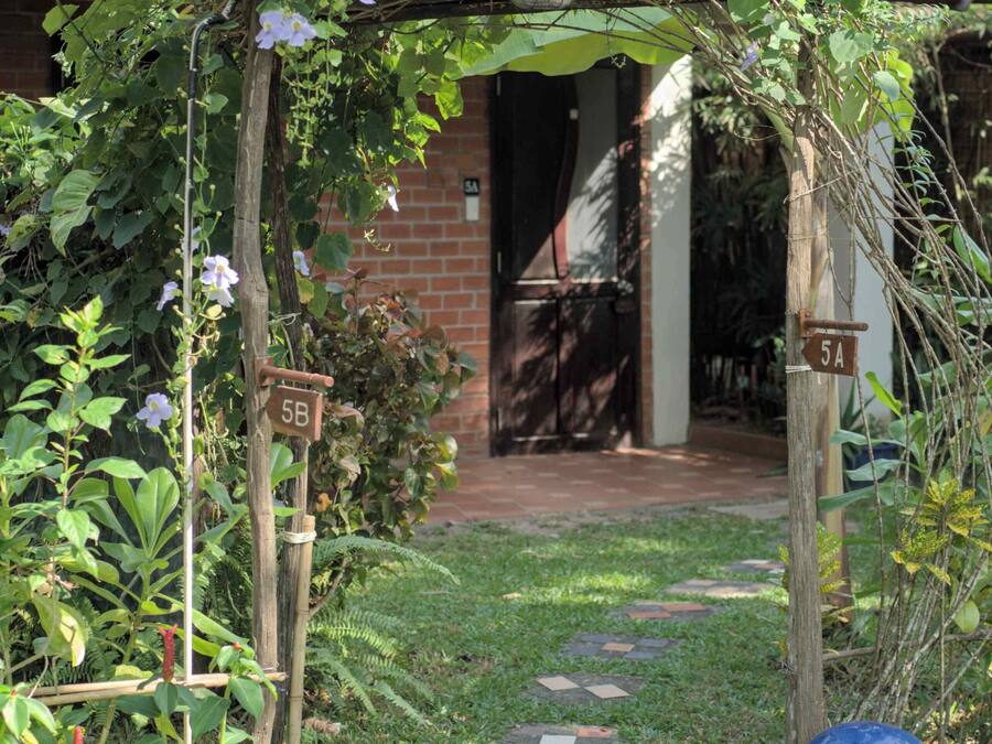 A garden entrance with a wooden archway, a brick pathway, and a blue spherical object.
