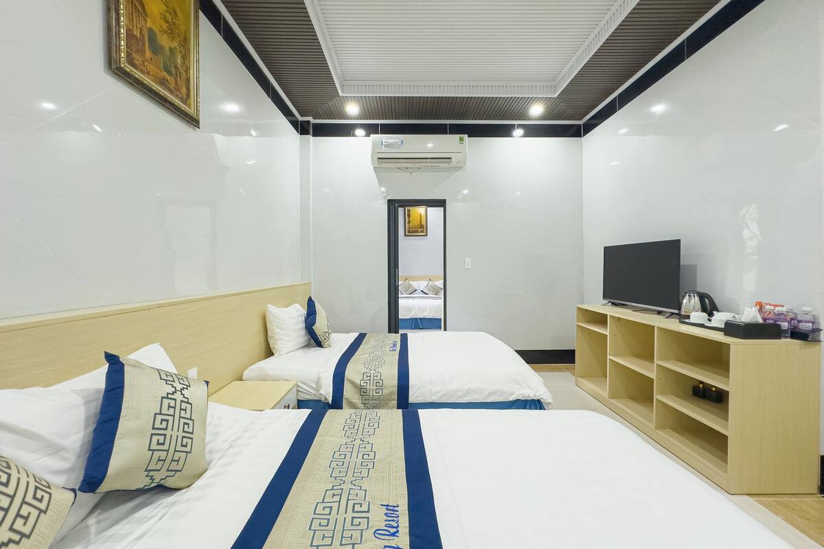 A hotel room with two beds, a television, a coffee maker, and a shelf with toiletries.