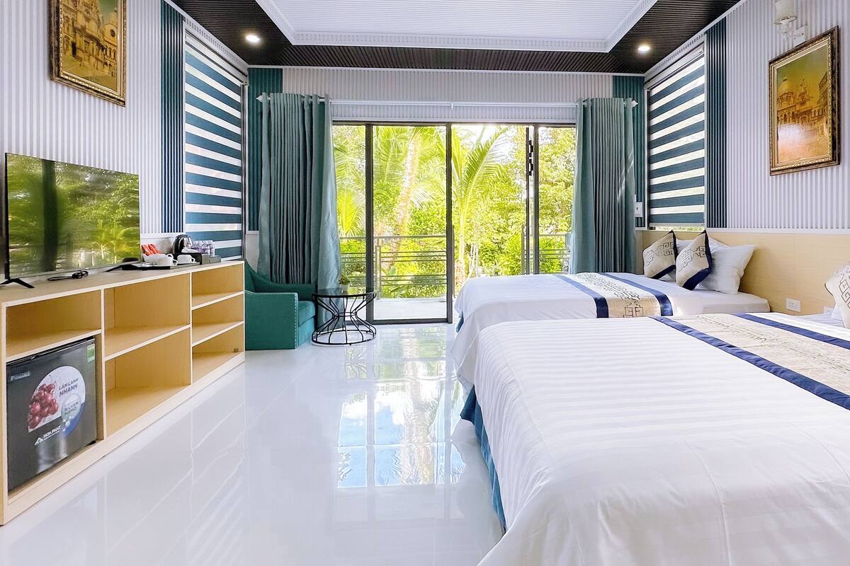 A modern bedroom with two beds, a TV, and a bookshelf.