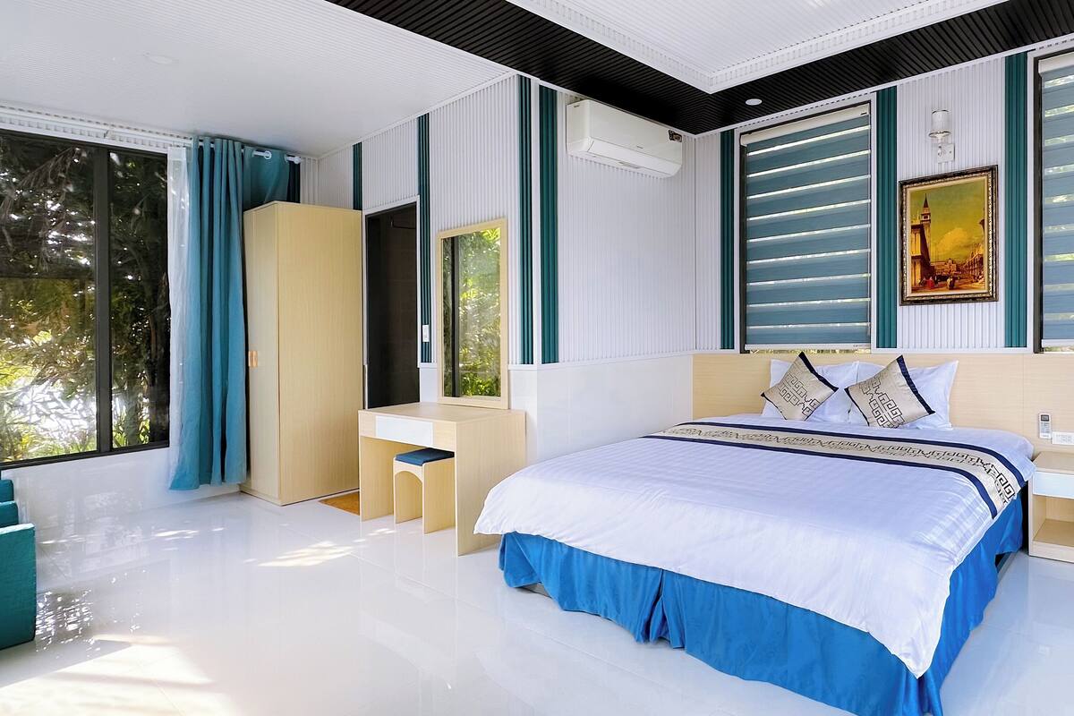 A modern bedroom with a large bed, a desk, and a wardrobe.