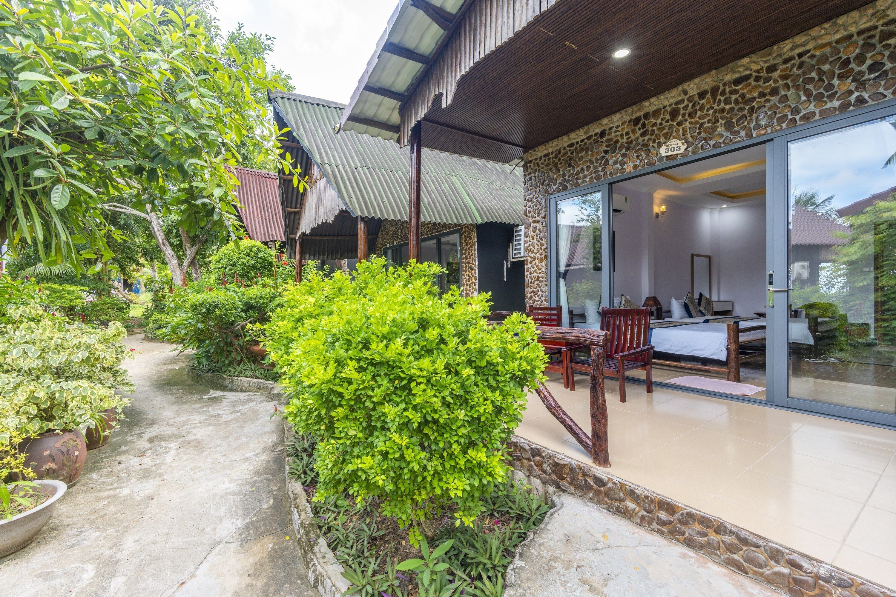 A hotel with a stone facade, large glass windows, and a garden path.