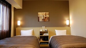 Une chambre d’hôtel avec deux lits, une tête de lit dotée d’une étagère, une œuvre d’art accrochée au mur et deux lampes de chevet.