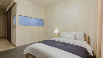 A hotel room with a bed, a nightstand, a lamp, and a wall-mounted TV.