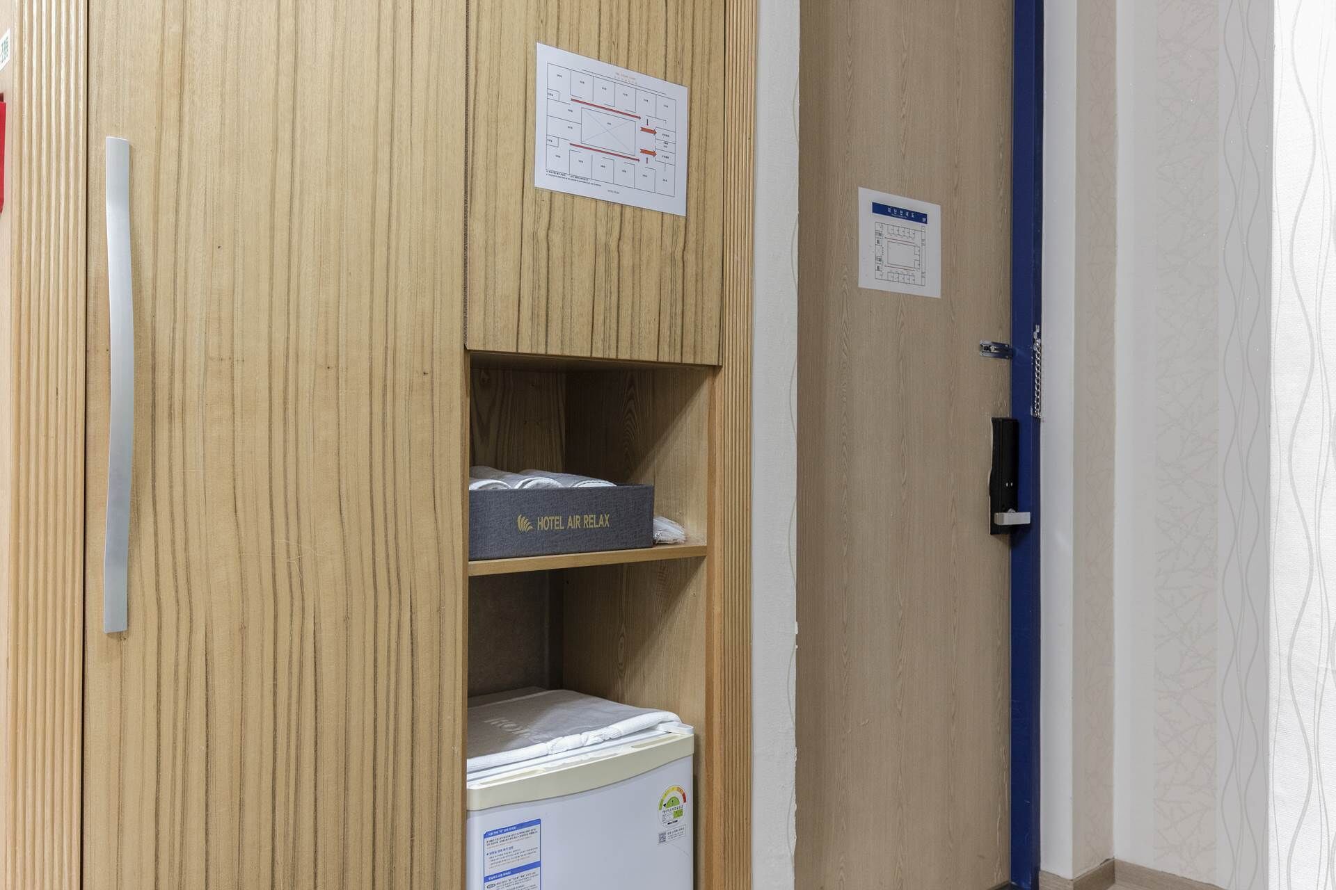 A wooden wardrobe with a mattress labeled "HOTEL AIR RELAX" and a small refrigerator.