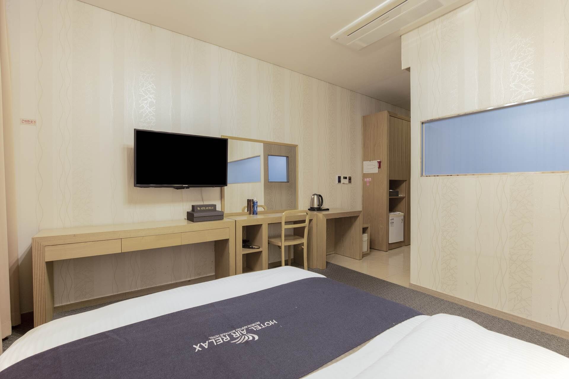 A hotel room with a bed, a desk, a television, and a wardrobe.