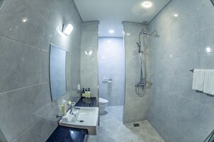 Une salle de bain moderne avec un grand miroir, un lavabo, des toilettes et un espace douche.