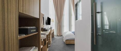 Una habitación de hotel con cama, escritorio con computadora, televisor y armario.