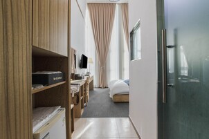 Une chambre d’hôtel comprenant un lit, un bureau avec un ordinateur, une télévision et une armoire.