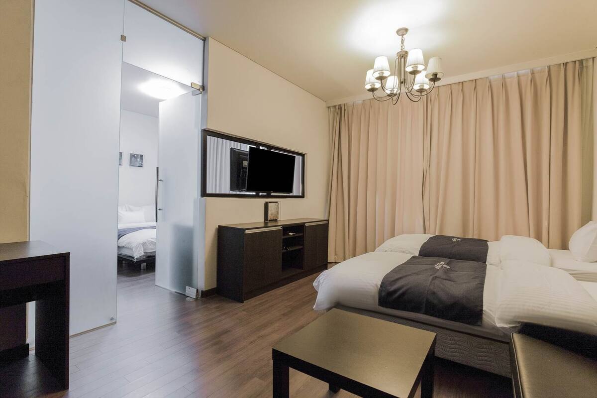 A hotel room with a bed, a desk, a television, and a chandelier.
