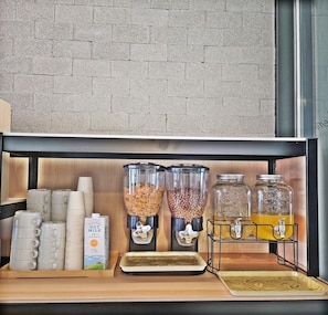 A breakfast bar with cereal dispensers, milk cartons, and a beverage dispenser. - Hotel Air Relax (Incheon)