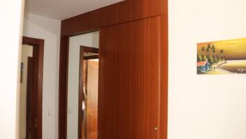 Una habitación con una puerta de madera, un cuadro de un paisaje y una pared blanca.