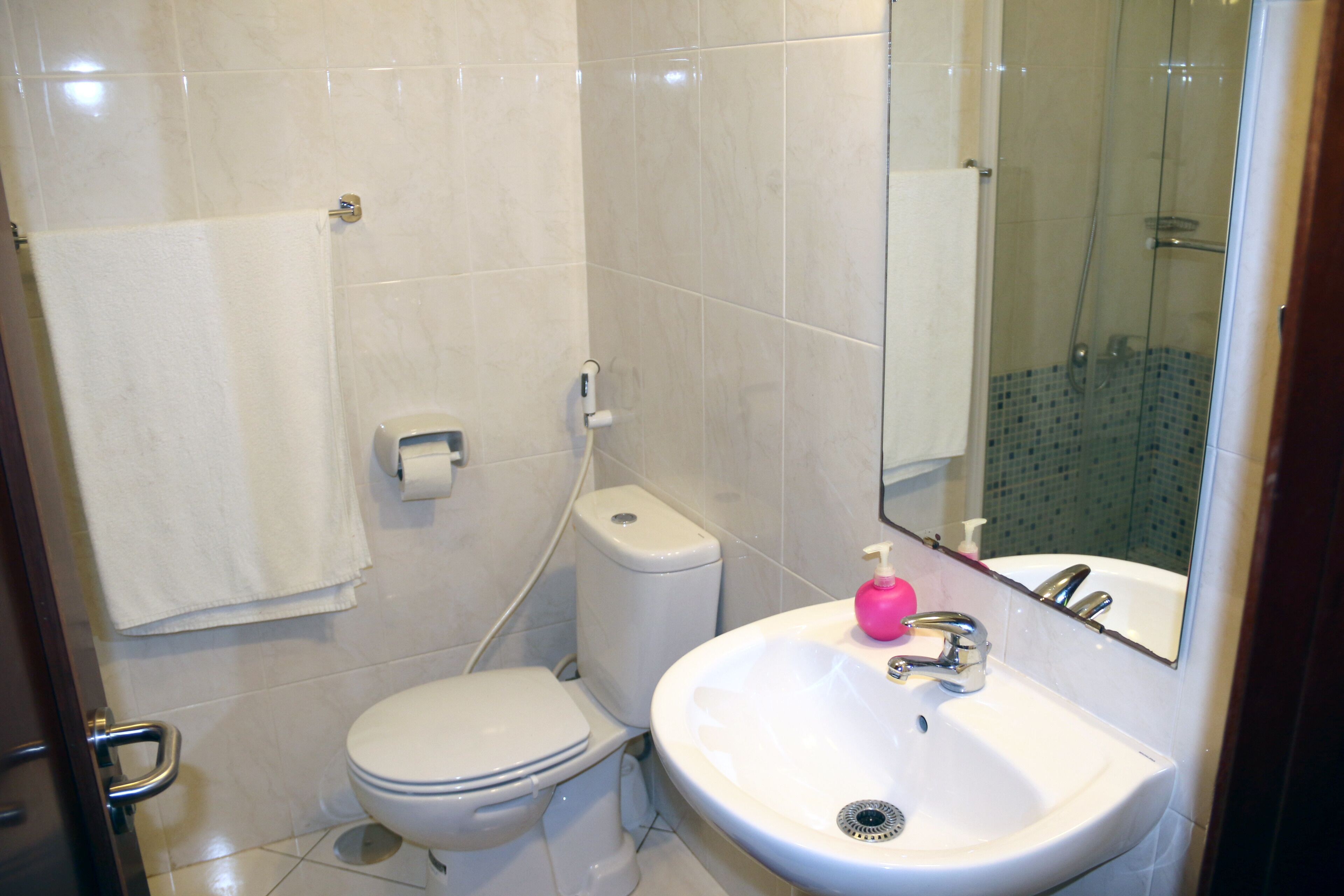 Et badeværelse med toilet, vask og bruser.