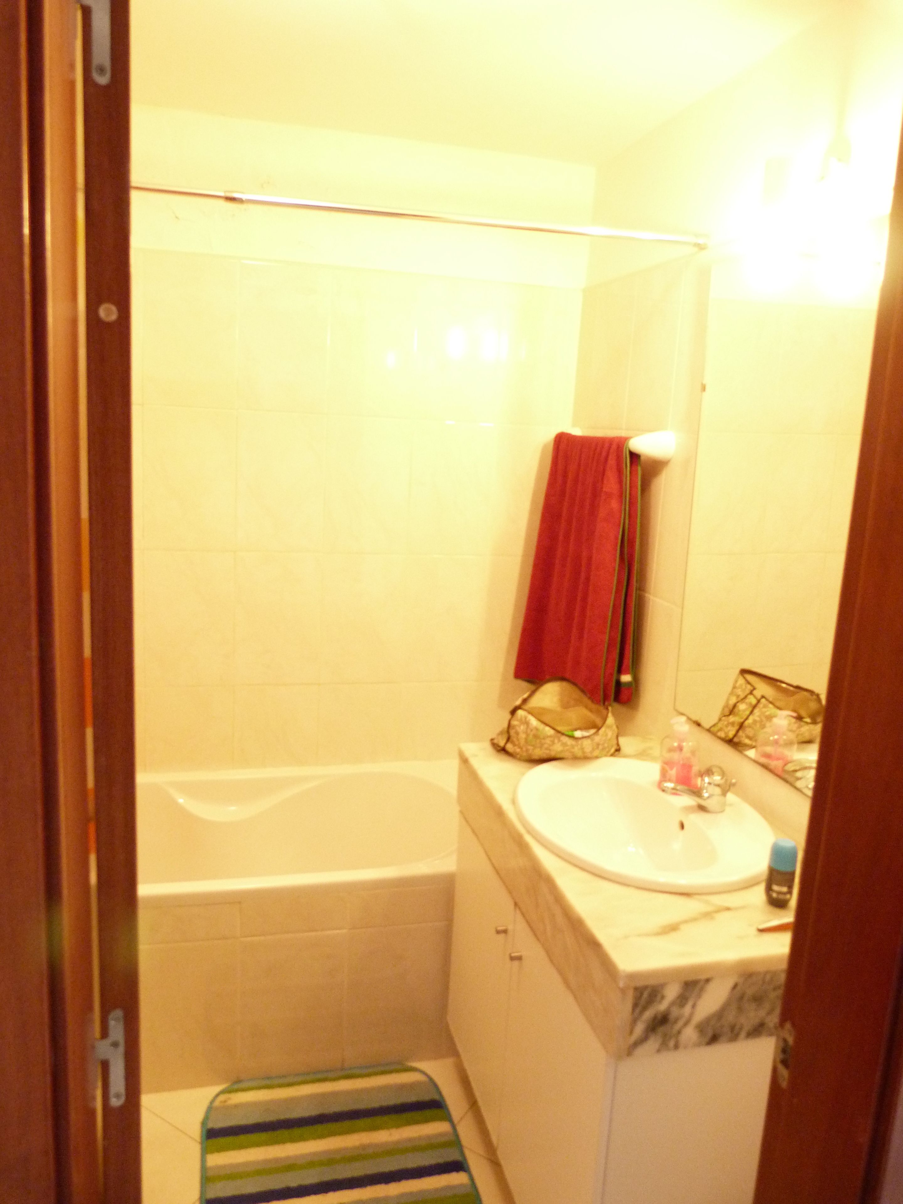 A small bathroom with a bathtub, a sink, and a mirror.