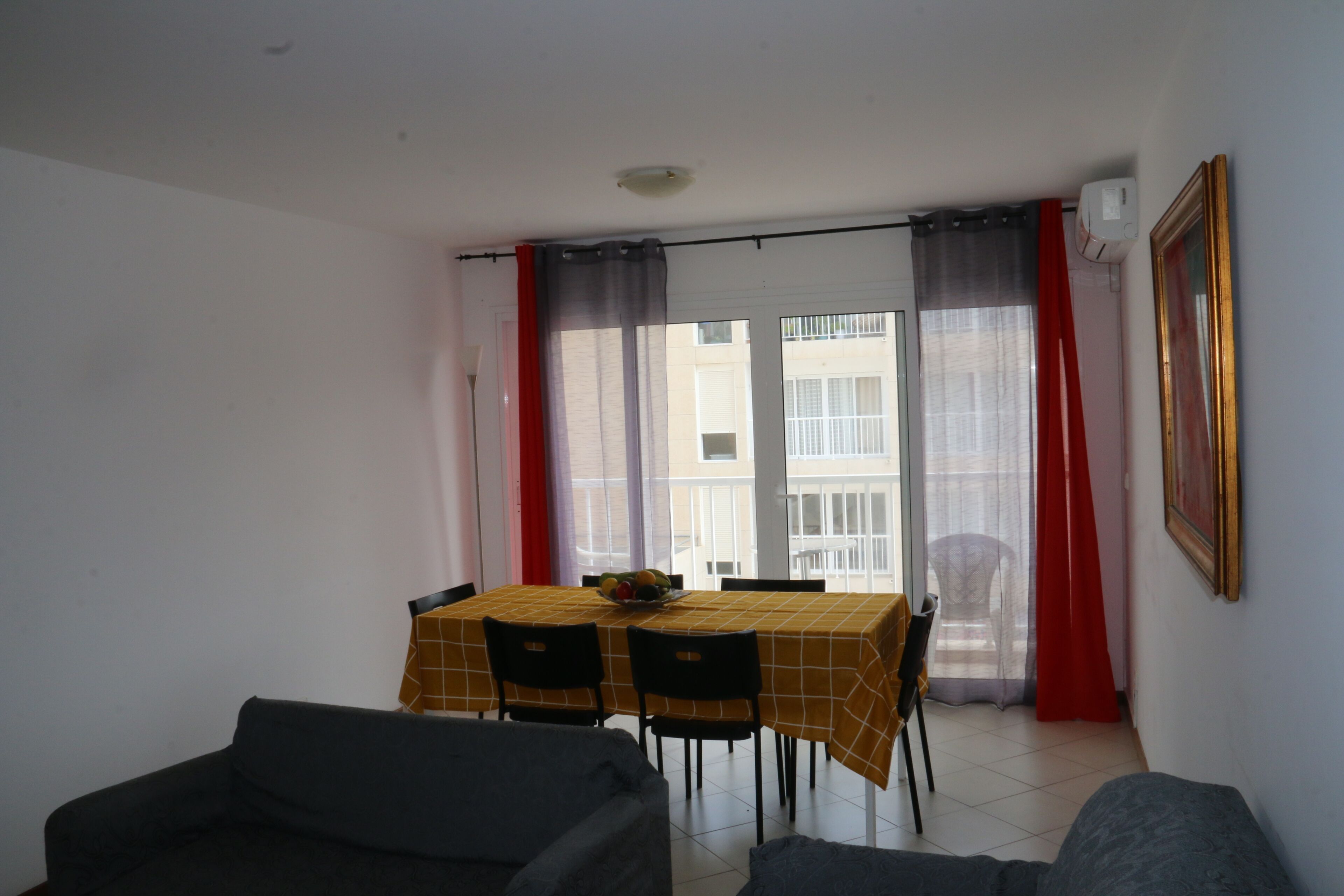 Uma área de refeições com mesa e cadeiras, uma varanda com vista e um quadro na parede.