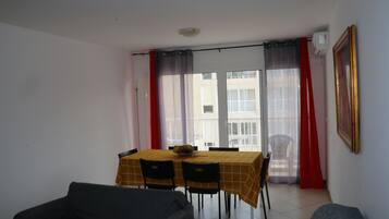Uma área de refeições com mesa e cadeiras, uma varanda com vista e um quadro na parede.