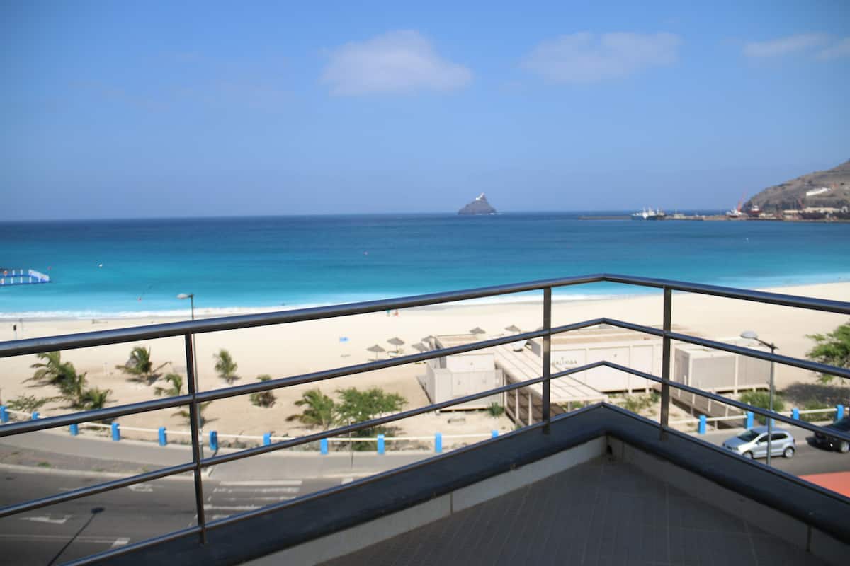 A balcony with a view of a beach and ocean.