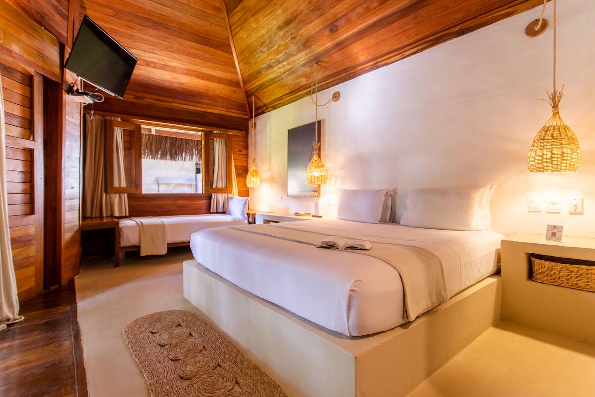A wooden room with a bed, a TV, and a window with curtains.