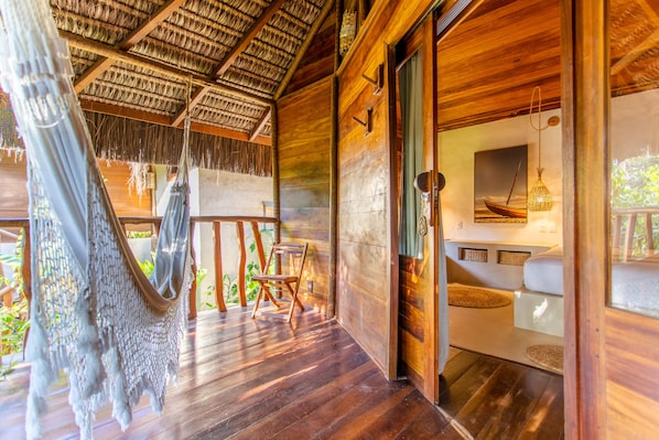 Una cabaña de madera con techo de paja, una hamaca y una terraza de madera.