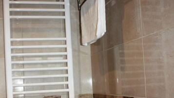 A bathroom with a white towel rack holding two towels, a white towel rack with a single towel, and a white towel rack with two towels.