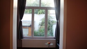 A room with a large window, a radiator, and a small table with fruit. - Eu B&B (Brussels)