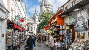 A bustling street with shops and a prominent domed building in the background. - Hotel de France (Paris)