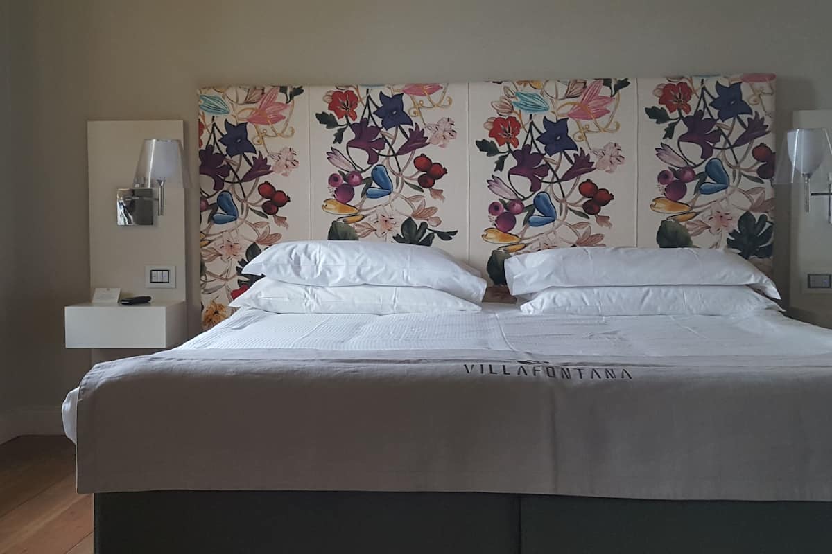 Een opgemaakt bed met witte lakens in een hotelkamer.