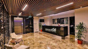 Een moderne hotel lobby met een receptiebalie, een zithoek en een houten plafond.
