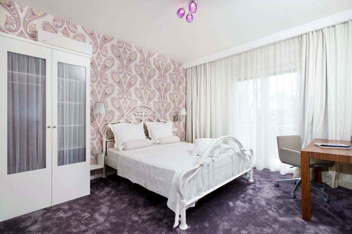 A bedroom with a bed, a desk, a chair, and a wardrobe.