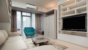 A modern living room with a sofa, a teal armchair, a coffee table, and a TV on a white wall. - Boban Luxury Suites (Split)