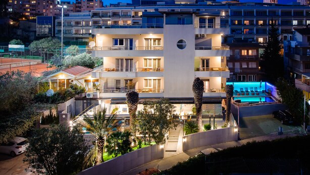 A modern hotel with multiple floors, outdoor swimming pool, and well-lit balconies. - Boban Luxury Suites (Split)