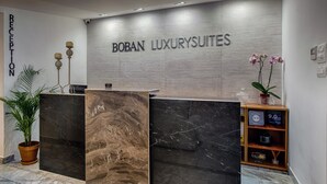A reception area with a marble floor, a reception desk with a marble top, and a wall with the text "BOBAN LUXURYSUITES". - Boban Luxury Suites (Split)